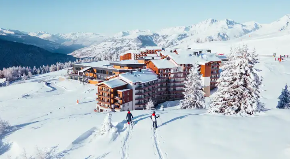 ista aérea de resort Club Med nos Alpes cercado por montanhas nevadas.